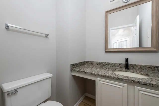 a bathroom with a granite countertop sink a toilet and a mirror