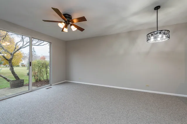 an empty room with windows and ceiling fan