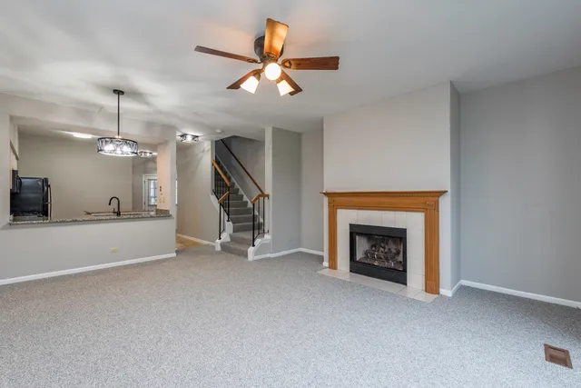 an empty room with windows fireplace and a ceiling fan