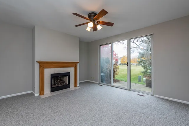 an empty room with fireplace fan and windows