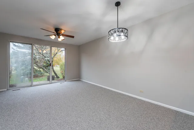 a view of a livingroom with a chandelier fan and a large window