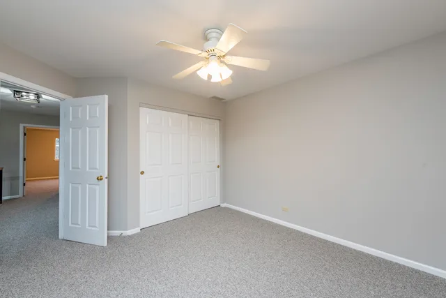 an empty room with closet and a chandelier fan