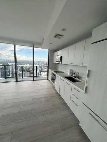 a large white kitchen with granite countertop a large window and a white counter top
