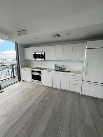 a kitchen with a refrigerator a stove top oven and a hard wood floor