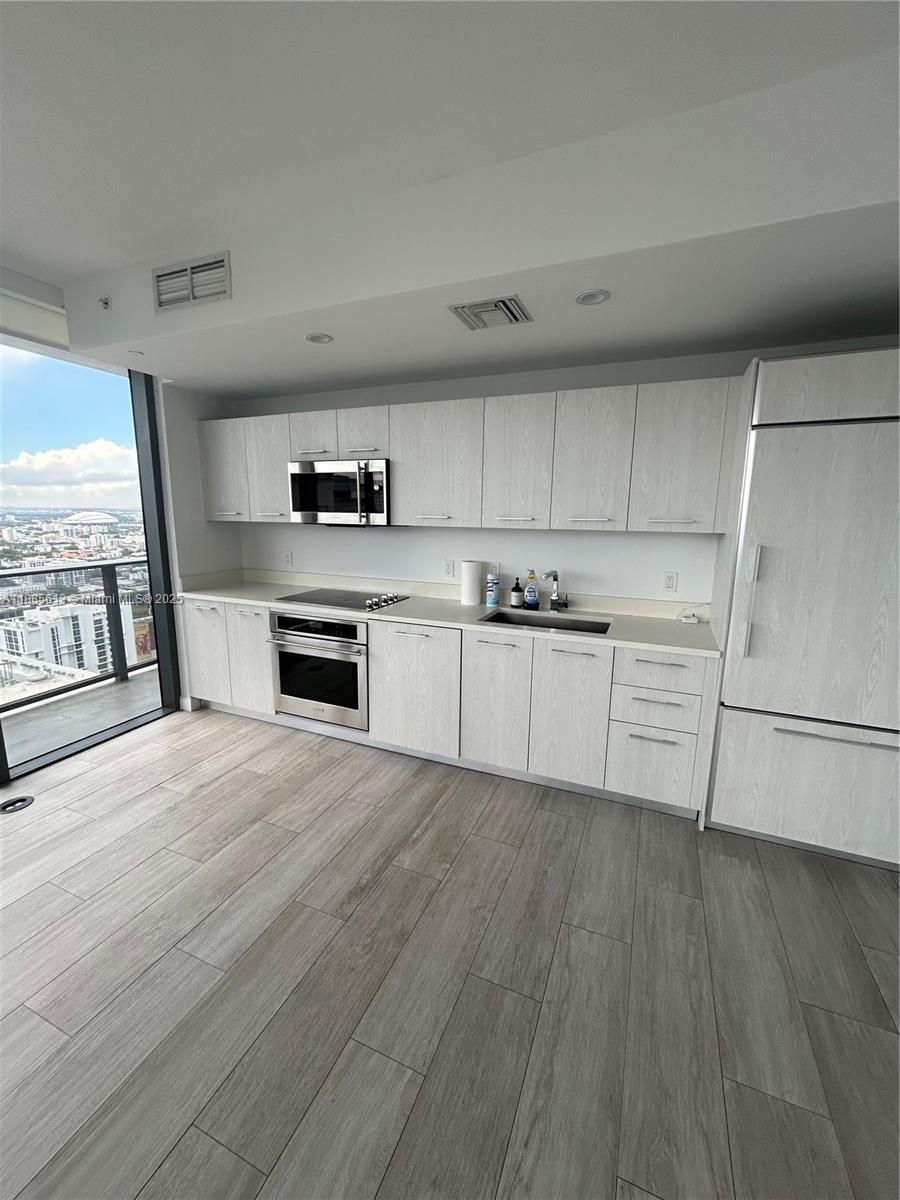 55 Southwest 9th Street, Unit 3506 Miami, FL 33130 - Photo 4 of 17 a kitchen with a refrigerator a stove top oven and a hard wood floor