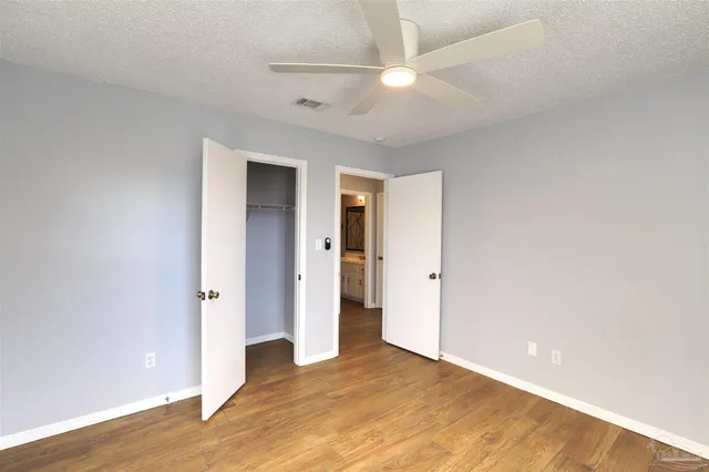 an empty room with wooden floor and ceiling fan