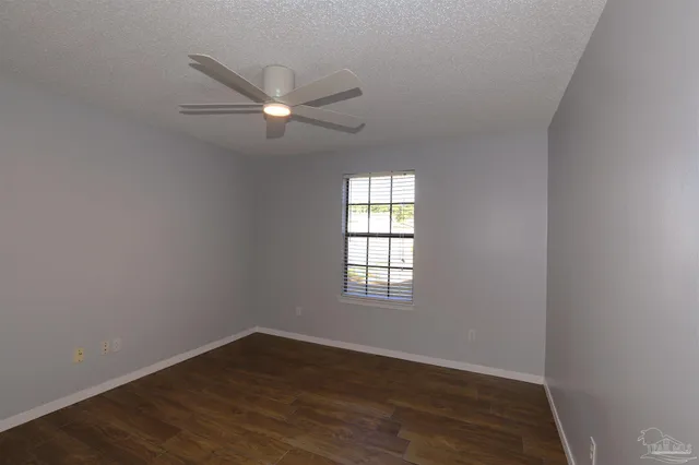 an empty room with wooden floor fan and windows