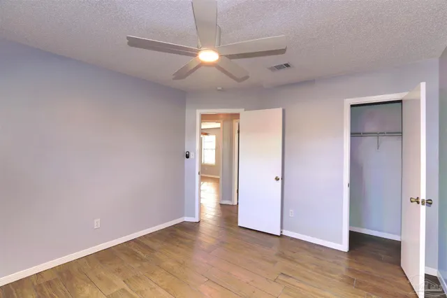 an empty room with wooden floor and a ceiling fan
