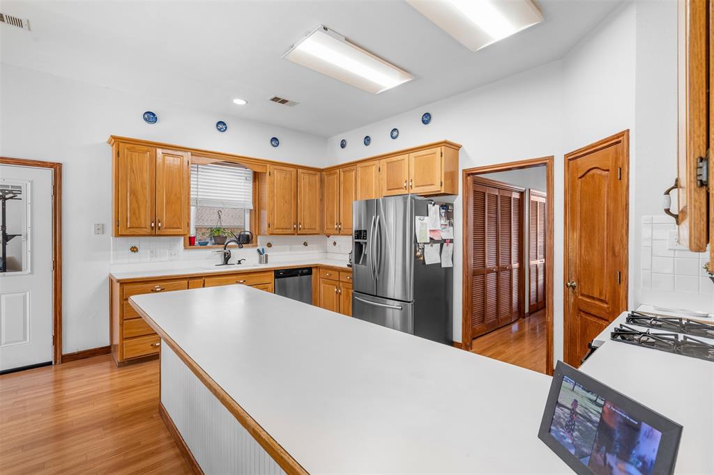 4502 Dexham Road Rowlett, TX 75088 - Photo 13 of 39 a large kitchen with stainless steel appliances a refrigerator a sink a stove a dining table and chairs with wooden floor