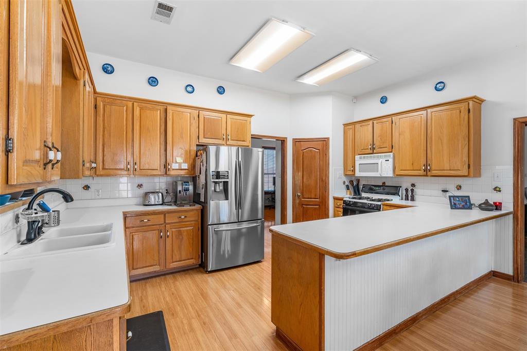 4502 Dexham Road Rowlett, TX 75088 - Photo 14 of 39 a kitchen with stainless steel appliances a refrigerator sink and wooden cabinets