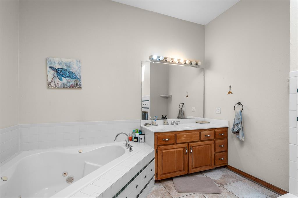 4502 Dexham Road Rowlett, TX 75088 - Photo 21 of 39 a bathroom with a tub a sink and a mirror