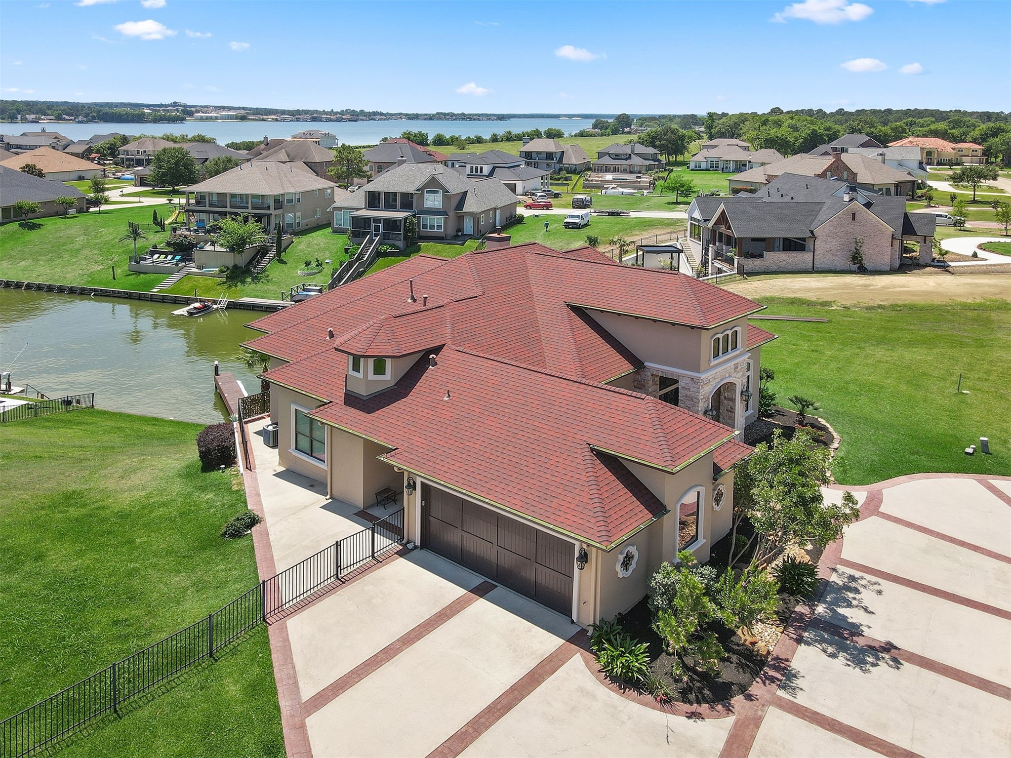 10896 Decatur Street Willis, TX 77318 - Photo 7 of 50 Discover this stunning lakeside home with a modern, spacious design, highlighted by a red-tiled roof and stone accents, offering serene water views, a private dock, large driveway, and a beautifully landscaped yard perfect for outdoor enjoyment.