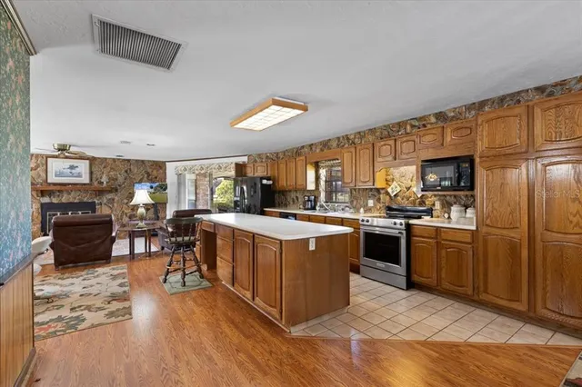 a kitchen with stainless steel appliances granite countertop a stove a sink dishwasher a refrigerator and a dining table with wooden floor