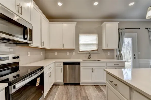a kitchen with stainless steel appliances a sink cabinets and wooden floor