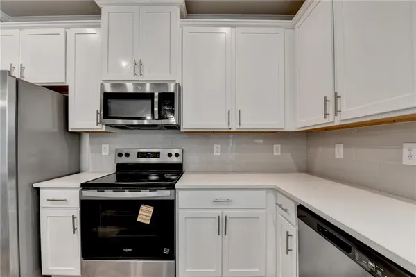 a kitchen with white cabinets and stainless steel appliances