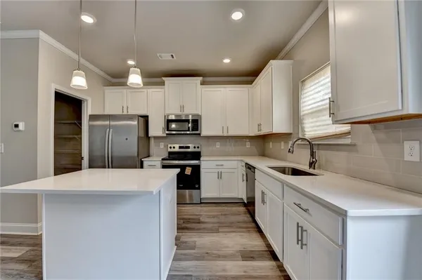 a kitchen with a sink a counter top space stainless steel appliances and cabinets