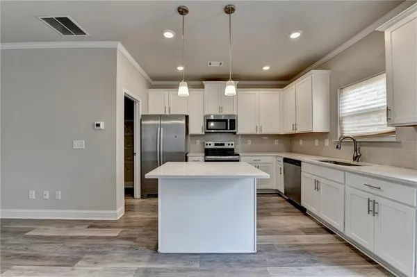 a kitchen with kitchen island a sink stainless steel appliances and cabinets