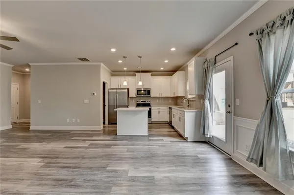 a kitchen with kitchen island granite countertop a stove a sink and white cabinets with wooden floor