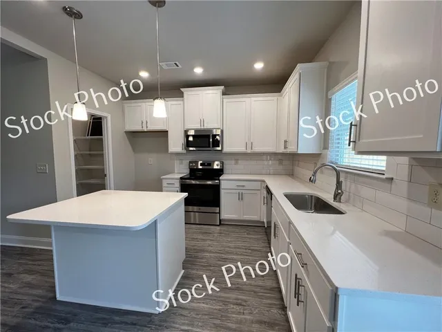 a kitchen with kitchen island granite countertop a sink a counter top space a stove and refrigerator