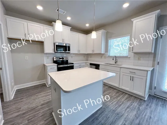 a kitchen with kitchen island a white counter top space a sink and cabinets