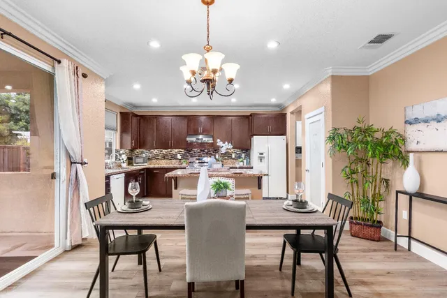 a kitchen with a refrigerator a stove a sink and a dining table with chairs