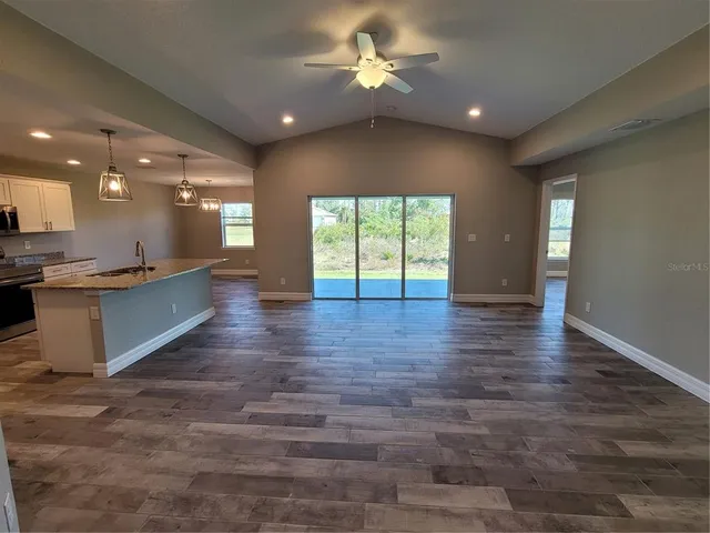 an empty room with wooden floor and a kitchen
