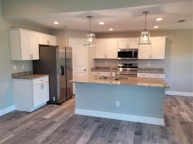 a kitchen with stainless steel appliances granite countertop a refrigerator a stove a sink and a microwave