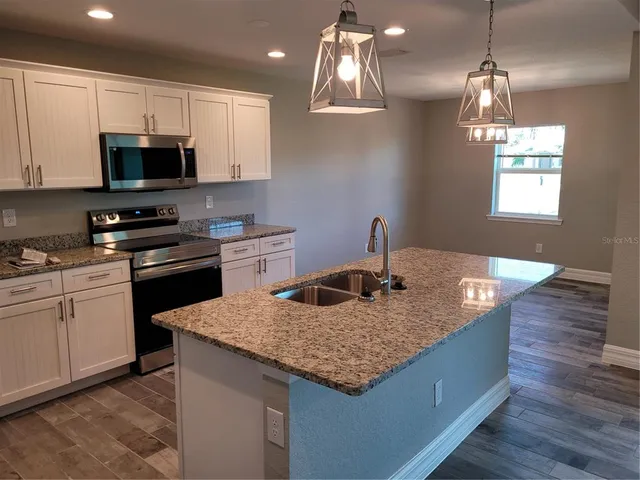 a kitchen with granite countertop a sink a counter top space and cabinets