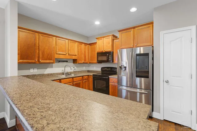 a kitchen with stainless steel appliances granite countertop a refrigerator a stove top oven a sink and dishwasher