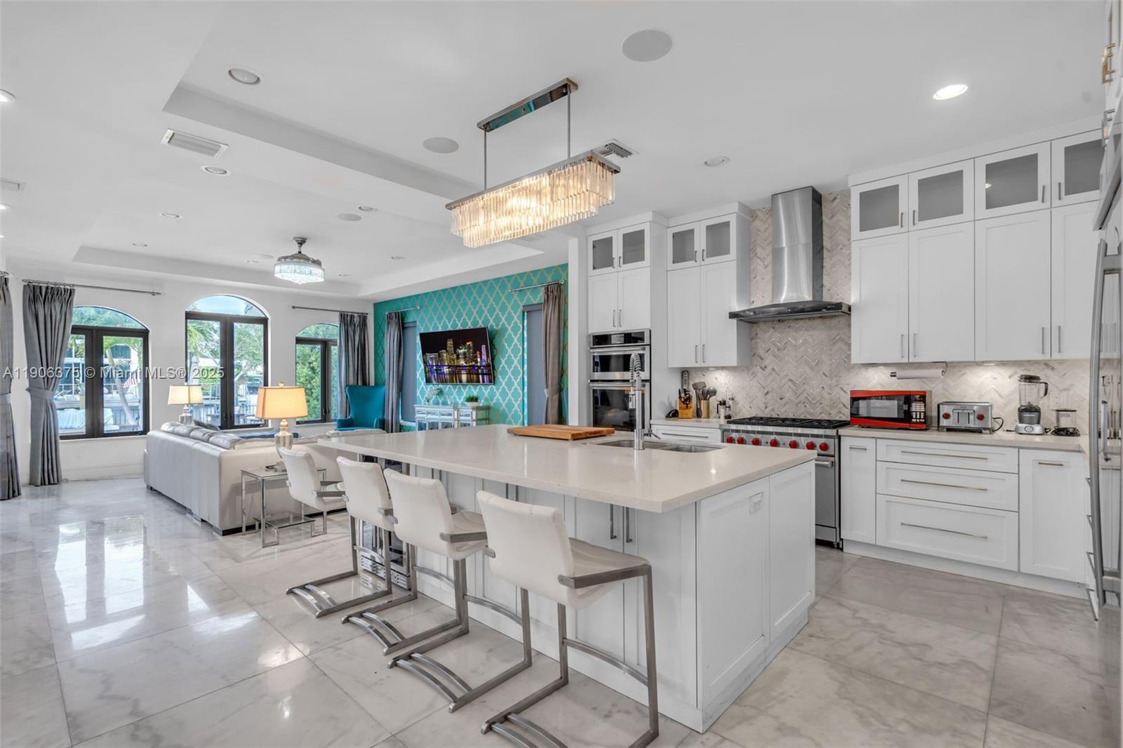 2085 Keystone Boulevard North Miami, FL 33181 - Photo 17 of 77 a large white kitchen with lots of counter space and chandelier