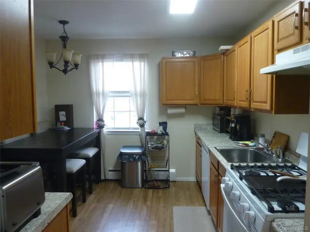 a kitchen with a stove a sink and wooden floor
