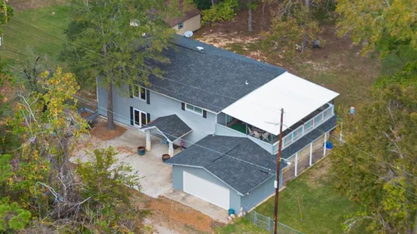 a view of a house with a yard and large trees