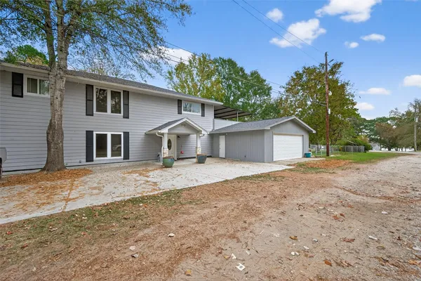 a front view of a house with a dirt yard and a garage