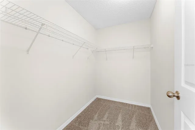 an empty room with a windows and chandelier fan