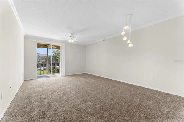 an empty room with a chandelier fan and windows