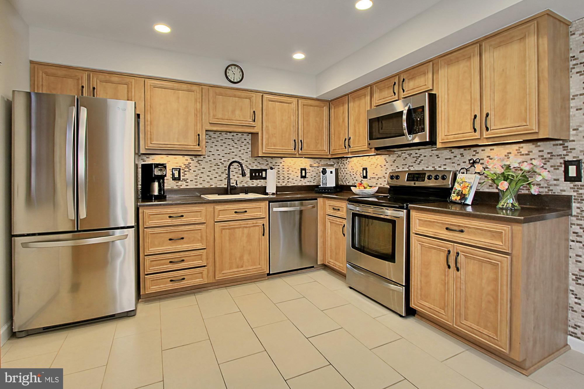 7013 Leestone Street Springfield, VA 22151 - Photo 4 of 36 a kitchen with white cabinets stainless steel appliances and a refrigerator