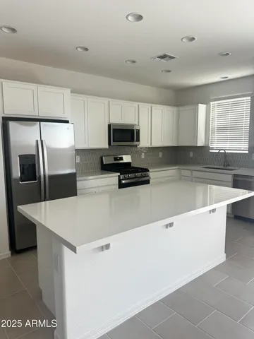 a kitchen with granite countertop a refrigerator and a stove top oven