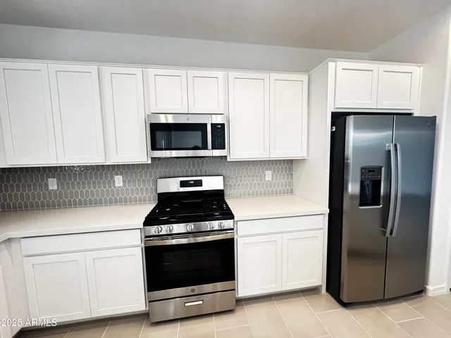 a kitchen with white cabinets and stainless steel appliances