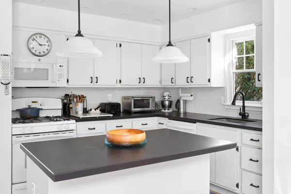 a kitchen with stainless steel appliances granite countertop a sink a stove and a white cabinets