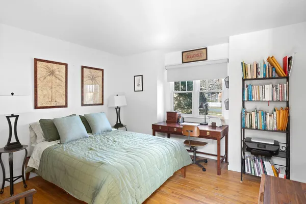 a bedroom with a bed a table and a book shelf