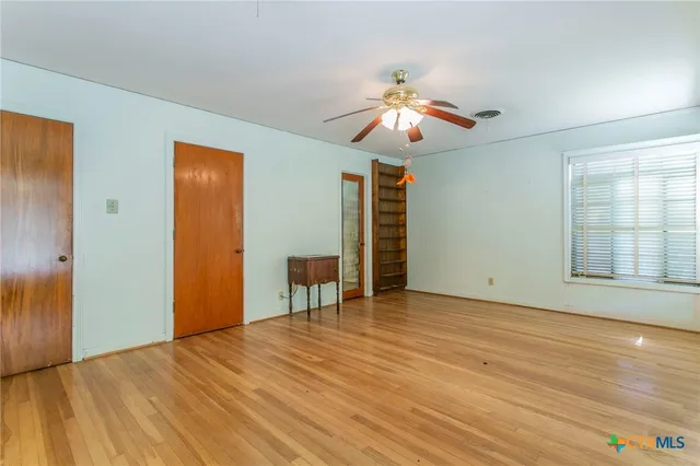a view of empty room with wooden floor and fan