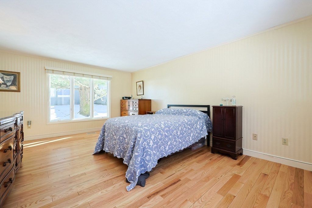 93 Potter Pond, Unit 93 Lexington, MA 02421 - Photo 23 of 42 a bedroom with a bed and wooden floor
