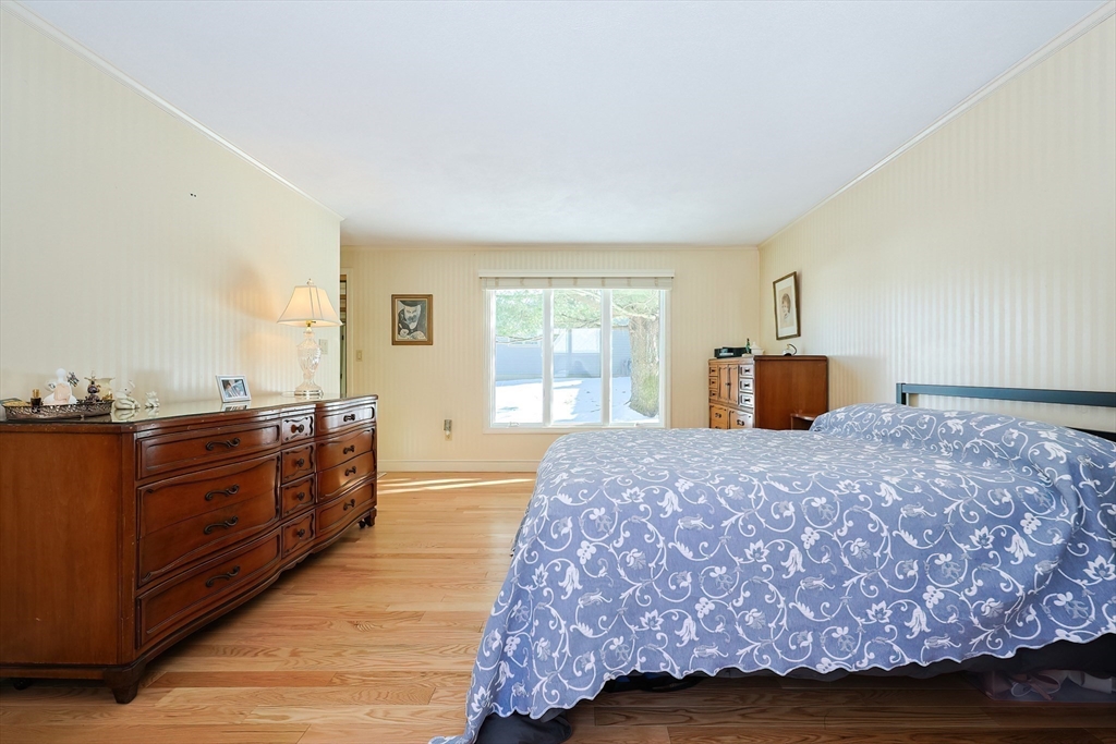 93 Potter Pond, Unit 93 Lexington, MA 02421 - Photo 24 of 42 a bedroom with a bed and wooden floor