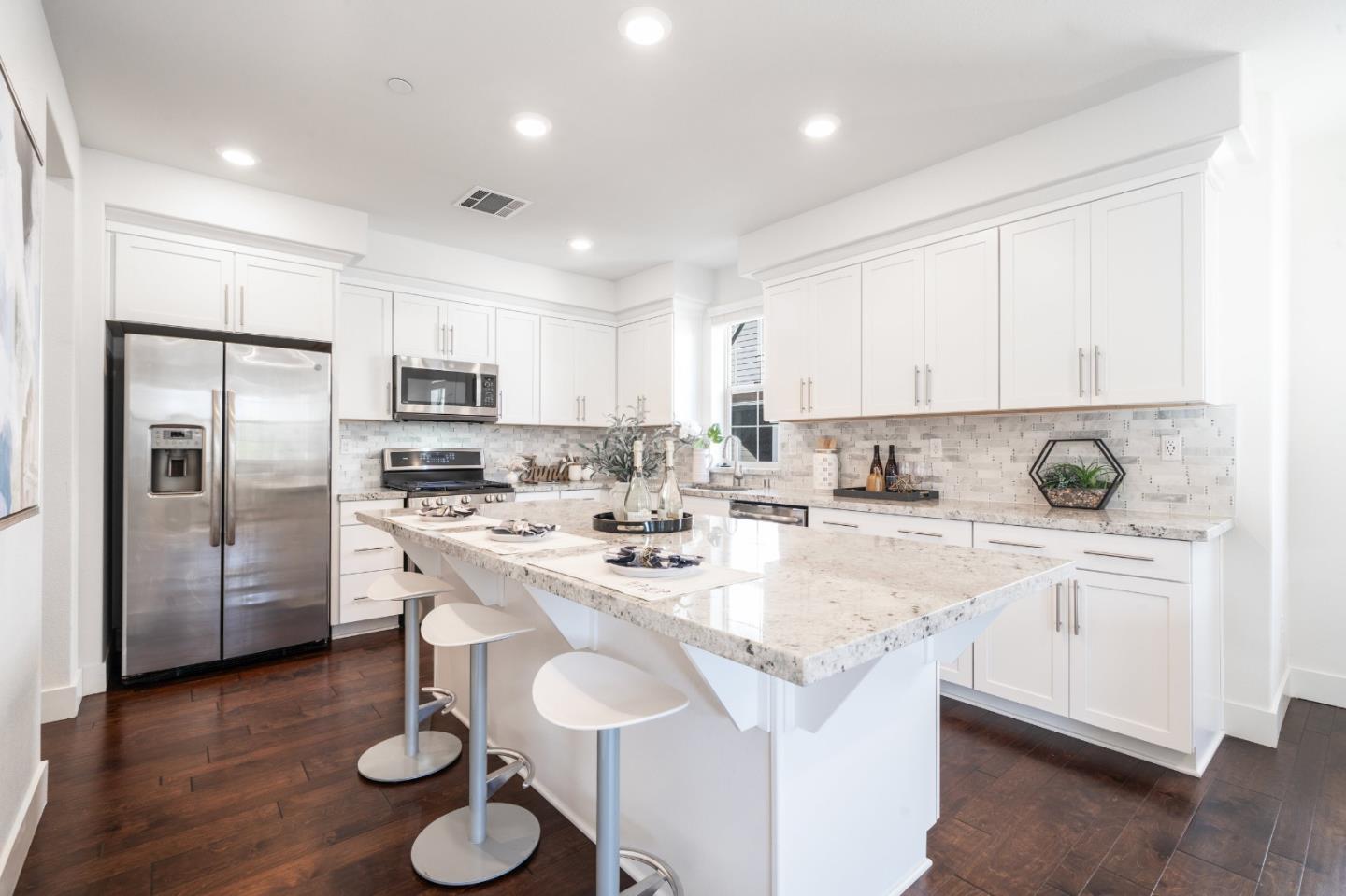8553 Seawind Way Newark, CA 94560 - Photo 14 of 30 a kitchen with stainless steel appliances granite countertop a sink a stove a refrigerator and white cabinets with wooden floor
