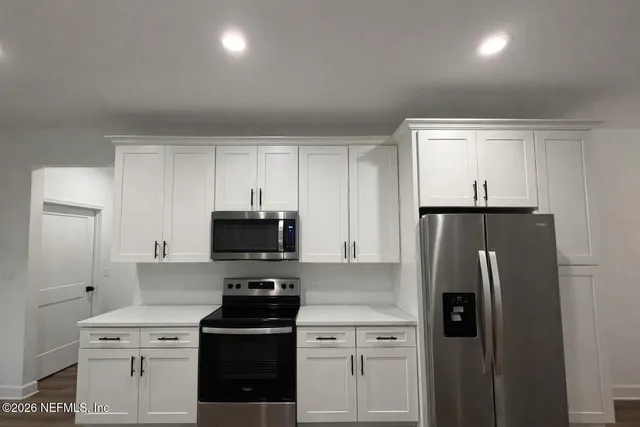 a kitchen with a refrigerator and a stove top oven