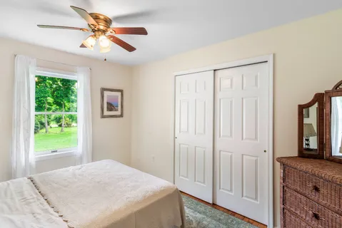 a bedroom with a bed a dresser and a large window