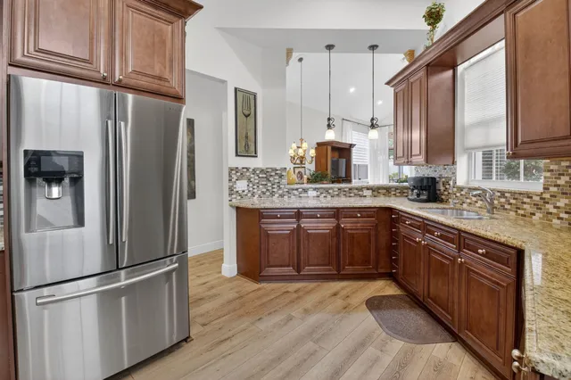 a kitchen with stainless steel appliances granite countertop a refrigerator a stove and a sink