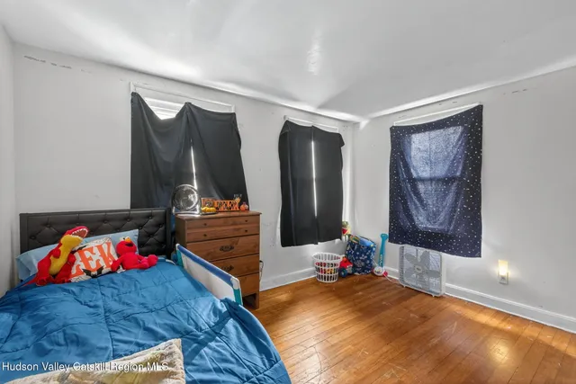a bedroom with a bed and dresser with wooden floor