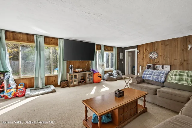a living room with furniture a flat screen tv and a large window