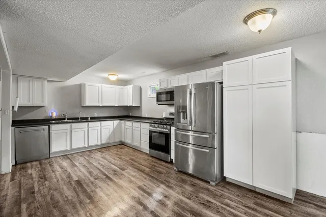 a large kitchen with stainless steel appliances granite countertop a refrigerator and a stove top oven